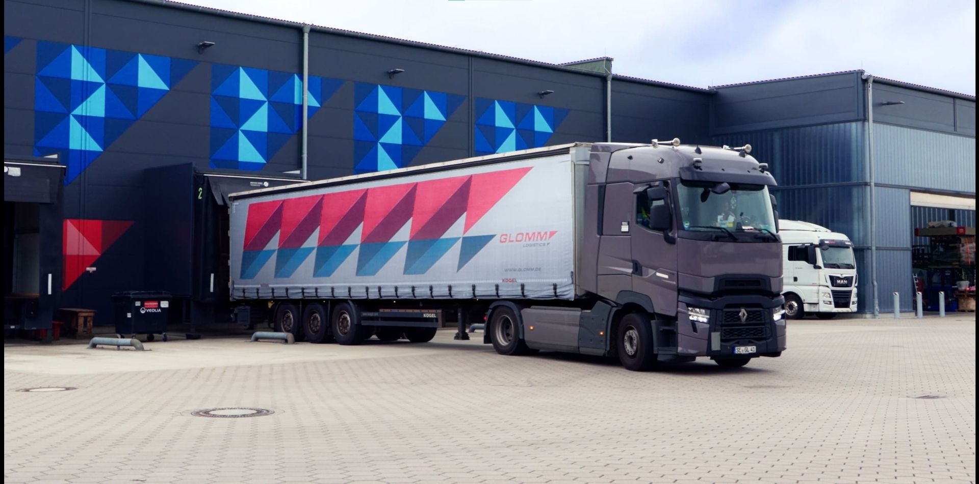 Ein LKW von Glomm Logistics vor dem Firmengebäude wird ausgeladen und neu beladen